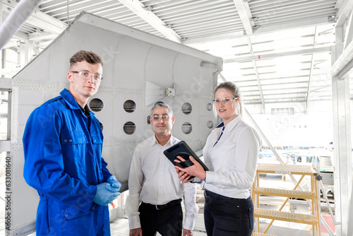 Workers with digital tablet in airplane hangar photo