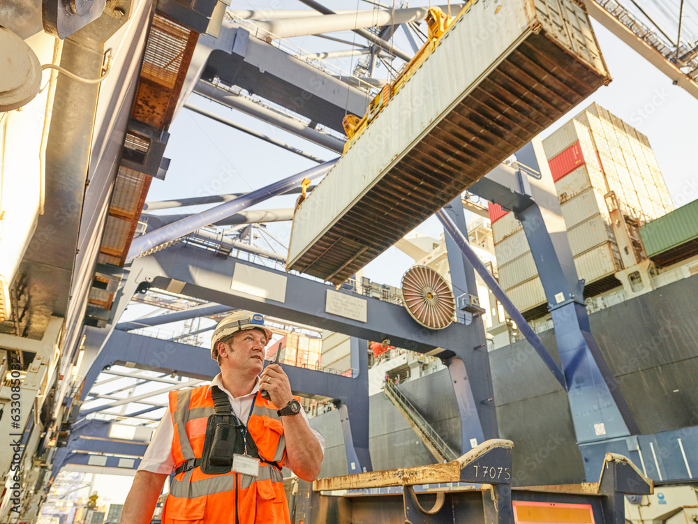 Dock manager communicating with crane driver to load cargo to lorry Dock manager communicating with crane driver to load cargo to lorry