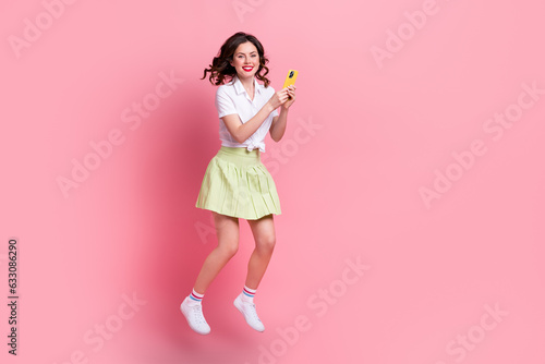 Full length photo of carefree sweet girl dressed white top jumping high empty space isolated pink color background