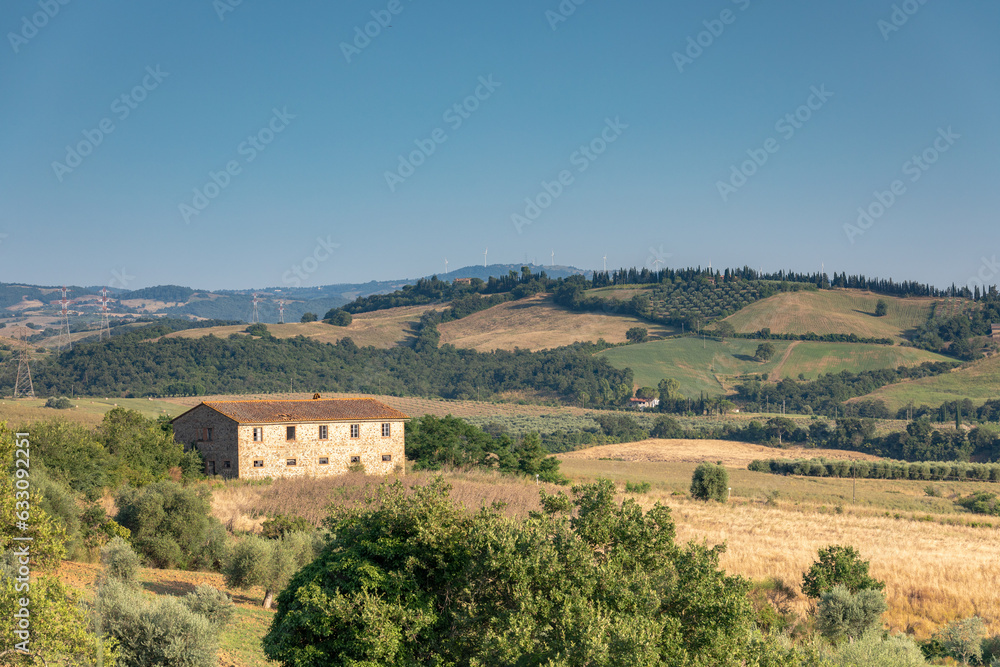 Traditional Tuscan landscape with a stone building in the foreground