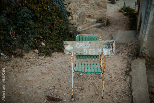 Rusted chair with a wooden sign at Calo des Moro in Mallorca photo