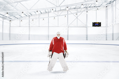Ice hockey goalkeeper wearing red uniform at an ice rink photo