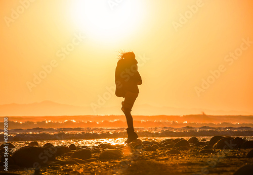 Silhouette of woman jumping on beach at sunset © Image Source