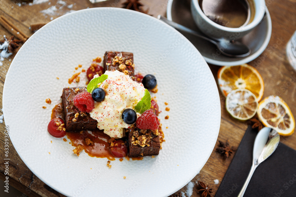 Brownie cake with salted caramel. Anglaise foam, raspberry sauce, praline nut and fresh berry. Delicious sweet dessert food closeup served for lunch in modern gourmet cuisine restaurant Brownie cake with salted caramel. Anglaise foam, raspberry sauce, praline nut and fresh berry. Delicious sweet dessert food closeup served for lunch in modern gourmet cuisine restaurant