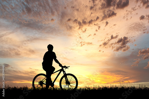 Silhouette of cyclist exercising in the meadow in the evening, fitness health care concept