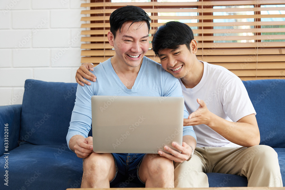 LGBT gay couple using laptop computer on sofa LGBT gay couple using laptop computer on sofa