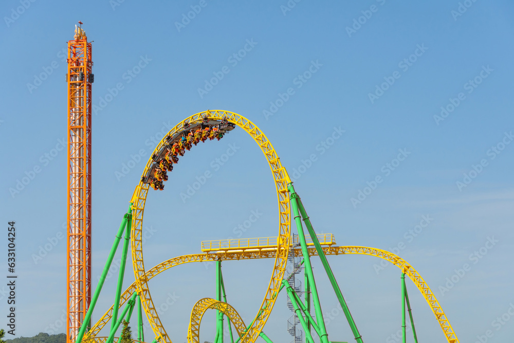 Amusement cart makes circular rides on a dead loop upside down at motion blur effect high speed, roller coaster yellow-green color.