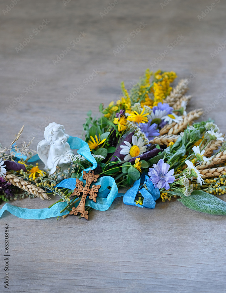 Herbs tied to sacred bouquets, cross and angel figurine on rustic wooden table close up. Herbal