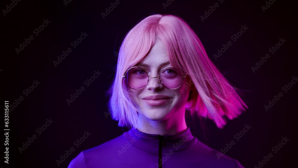 Beautiful woman in futuristic costume over dark background. Violet neon light. Girl in glasses smiling and looking at the camera. Beautiful woman in futuristic costume over dark background. Violet neon light. Girl in glasses smiling and looking at the camera.