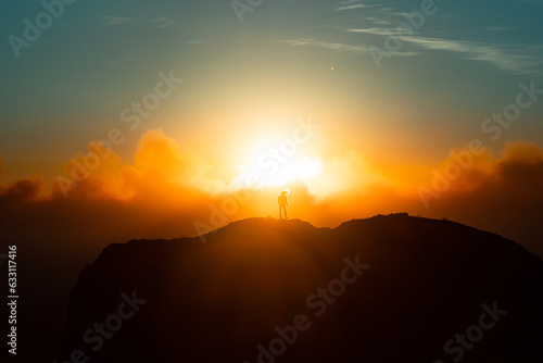 Woman standing in front of sun on mountain side rocks