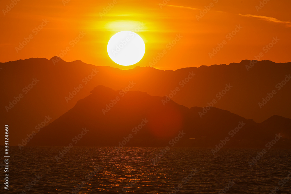Sunset at dusk hides behind Shark Island or Shark Island, intense orange and gold color seen  Bay beach, S
