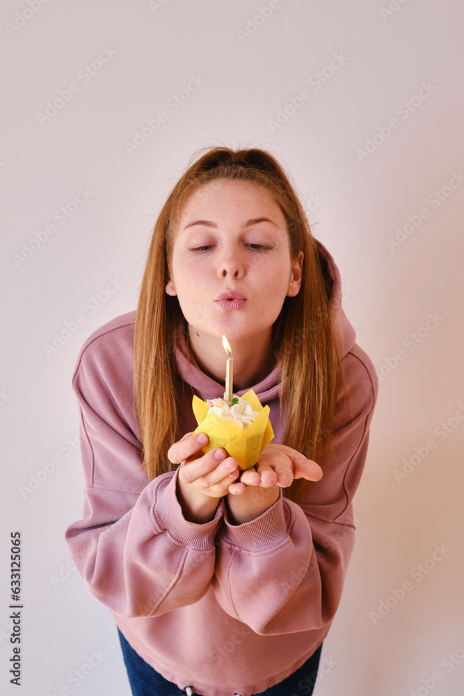 A young woman blows out a candle on a birthday sweet cake. Birthday wishes. Holidays and birthday concept A young woman blows out a candle on a birthday sweet cake. Birthday wishes. Holidays and birthday concept