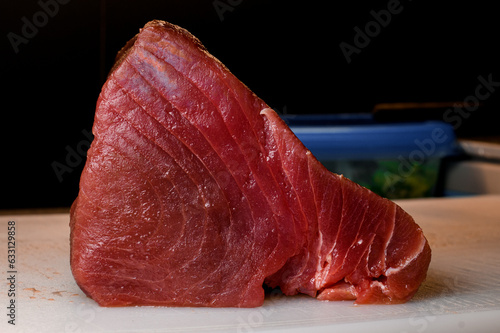 Delicious huge raw yellowfin tuna fish fillet on cutting counter. Black background photo