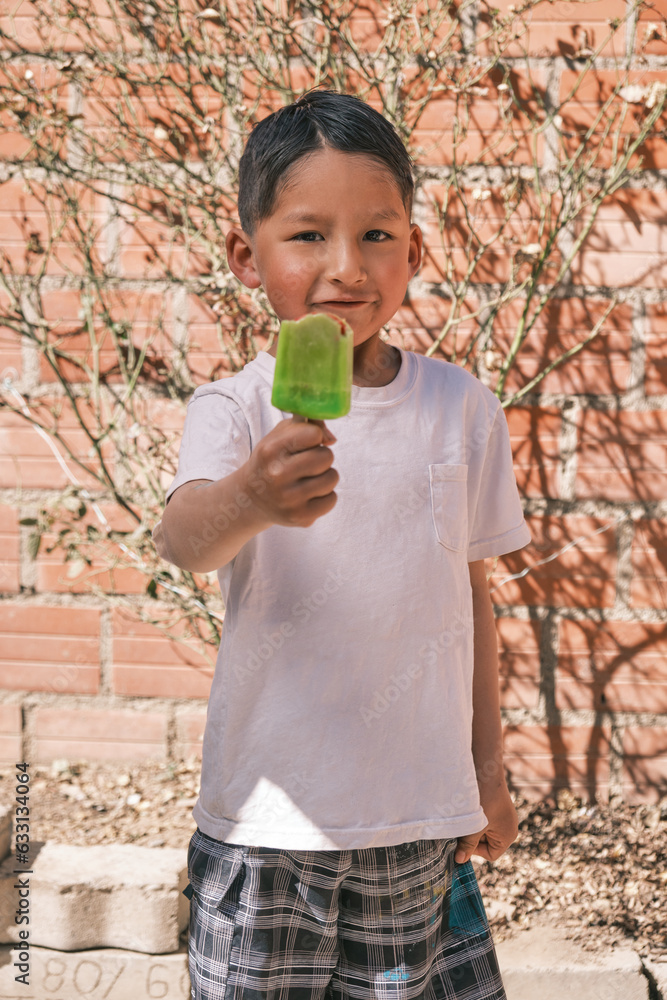 Fototapeta premium vertical photo of latin boy inviting an ice cream in summer on hot day in bolivia