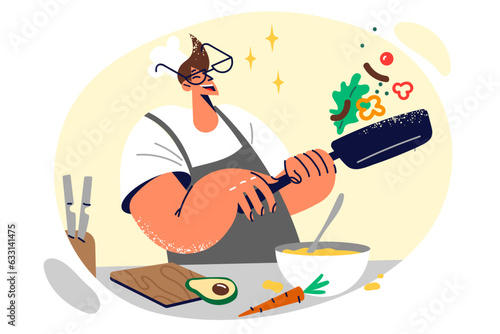 Man chef holds frying pan and prepares food, throws up ingredients to avoid burning during frying