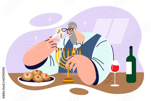 Elderly jewish man lights candles in minor before dinner and prepares to celebrate Hanukkah or Purim