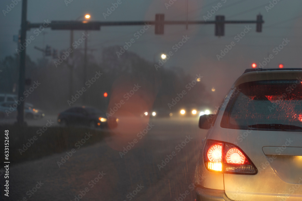 Cars driving on Florida city street at night during heavy rain with moving traffic during rush hour. Transportation system in USA