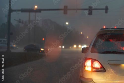 Cars driving on Florida city street at night during heavy rain with moving traffic during rush hour. Transportation system in USA