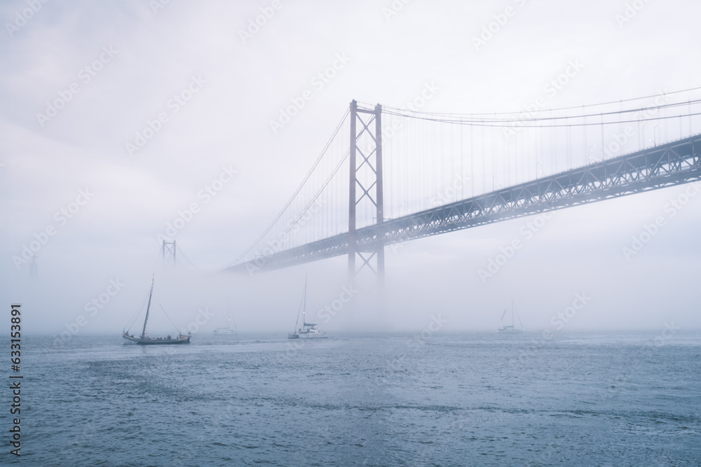View of 25 de Abril Bridge famous tourist landmark of Lisbon in heavy fog mist View of 25 de Abril Bridge famous tourist landmark of Lisbon in heavy fog mist