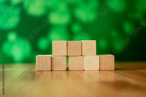 Wooden blocks neatly arranged on a wooden table, set against a softly blurred green summer background. Perfect for educational, lifestyle, and nature-themed projects.