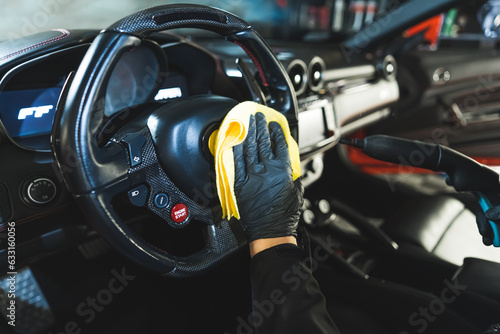 a mechanic with black gloves cleaning a car from inside at the repair shop. High quality photo
