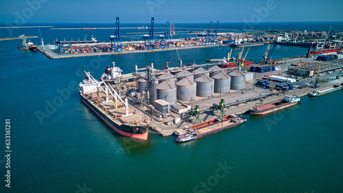 Canvas Print Loading grain into holds of sea cargo vessel in seaport from silos of grain storage
