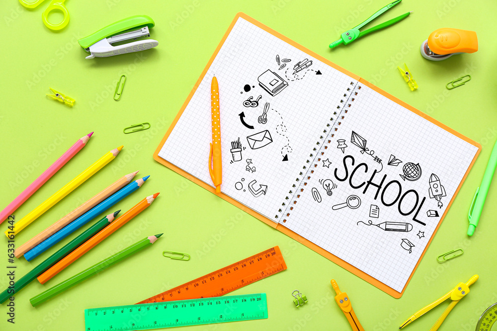 Notebook with word SCHOOL and different stationery on green background Notebook with word SCHOOL and different stationery on green background