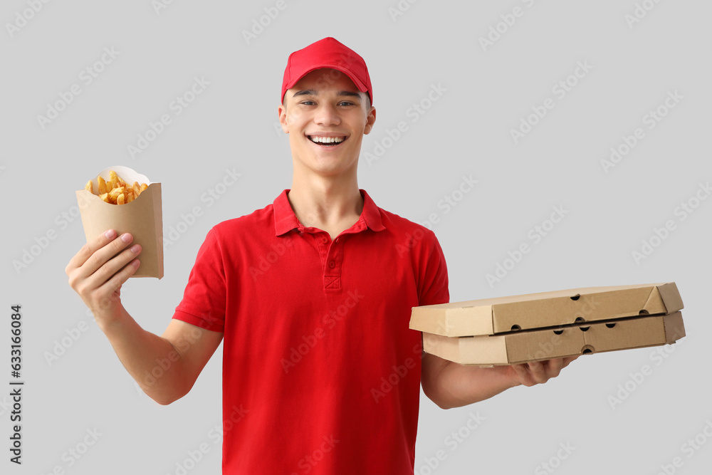 Young delivery man with french fries and pizza on light background Young delivery man with french fries and pizza on light background