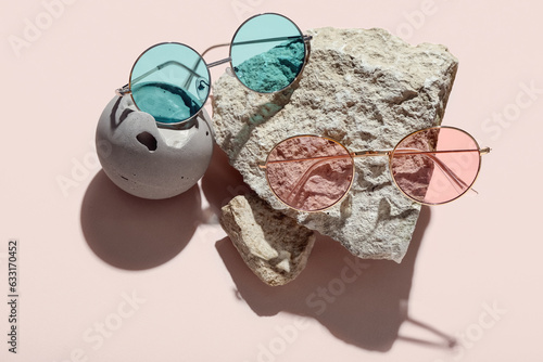 Stones with stylish sunglasses on pink background