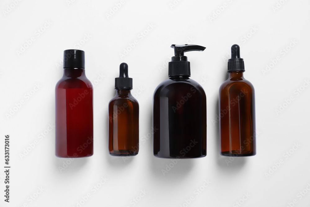 Bottles with different cosmetic products on white background, flat lay