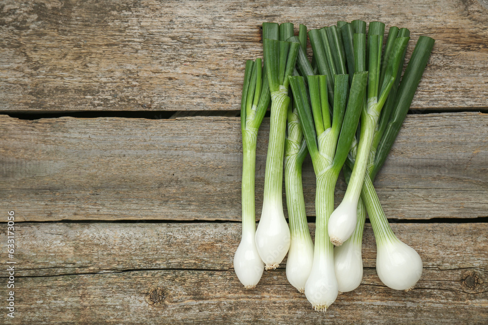 Whole green spring onions on wooden table, flat lay. Space for text Whole green spring onions on wooden table, flat lay. Space for text