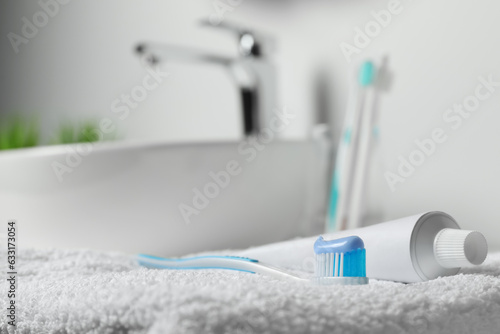 Plastic toothbrush with paste and tube on white towel in bathroom, closeup. Space for text © New Africa
