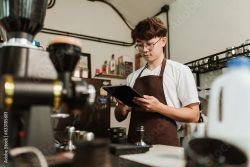 Asian man barista use digital tablet take orders service at coffee shop. SME business coffee shop concept.