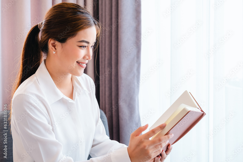 Asian woman reading book on comfort armchair beside the window in bedroom after get up in morning. Lazy Morning lifestyle concept.Beautiful young lady reading exciting story, having relaxing weekend Asian woman reading book on comfort armchair beside the window in bedroom after get up in morning. Lazy Morning lifestyle concept.Beautiful young lady reading exciting story, having relaxing weekend
