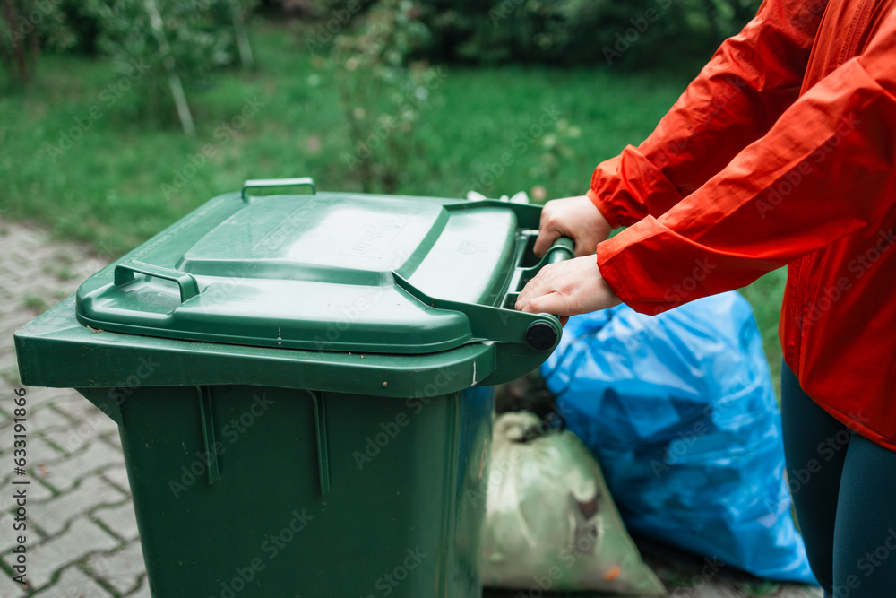 Adult happy 30s woman household taking out bin to the street on rubbish day. High quality photo
