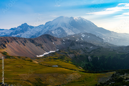 Golden hour view of Mount Rainier with grassy foothills under a blue sky