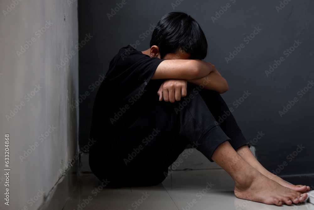 Full length of unhappy kid with mental health problem sitting on floor and covering head with hands. Full length of unhappy kid with mental health problem sitting on floor and covering head with hands.