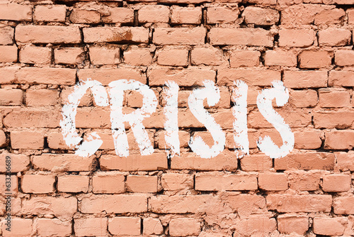 white chalk lettering text: crisis on old brick wall