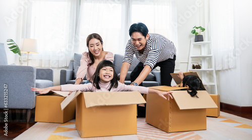 Asian family father mother daughter girl packing cardboard box relocation moving to new house, online marketing e-commerce unpacking stuff belongings home delivery. Lifestyle asian family together