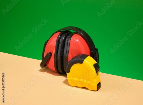 Red working headphones and yellow tape measure. DIY construction tools.