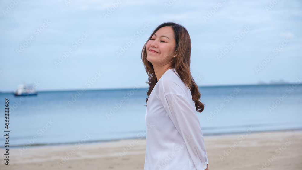 Portrait image of a beautiful young asian woman while strolling on the beach with the sea and blue sky Portrait image of a beautiful young asian woman while strolling on the beach with the sea and blue sky