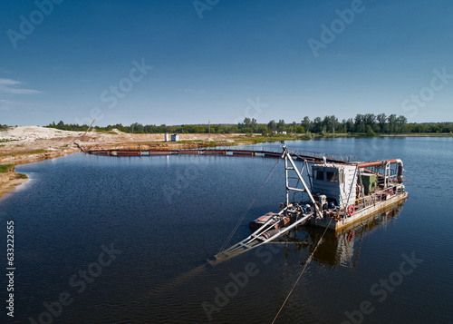 Fototapeta Suction dredger vessel works drawing up bottom mud on river