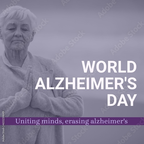 Composite of world alzheimer's day text over meditating senior caucasian woman by seaside