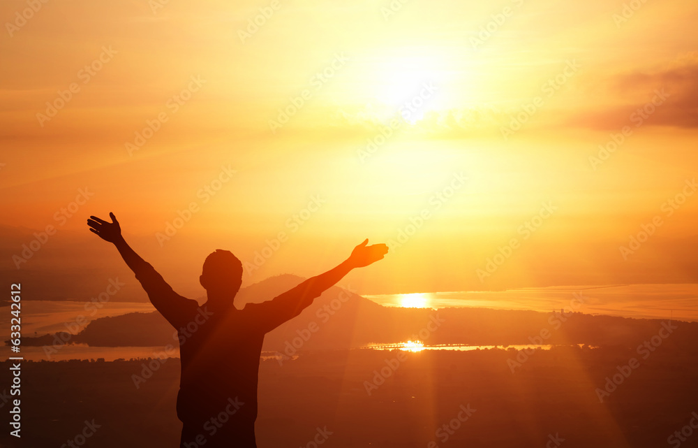 Man with arms raised in front of sun 