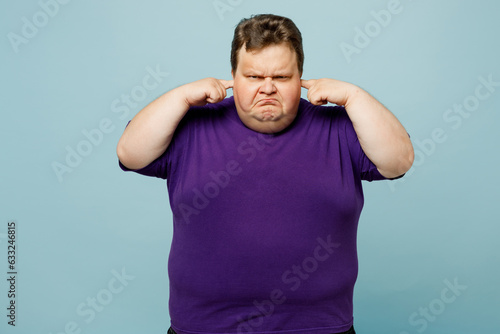 Photography Young sad chubby overweight man wears purple t-shirt casual clothes cover ears with hands fingers do not want to listen scream isolated on plain pastel light blue cyan background