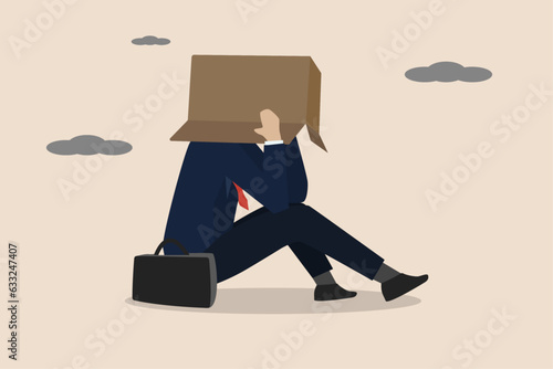 Business failure, work mistake, shame, bankruptcy or failed businessman concept, depressed businessman sitting alone covering his head with box in embarrassment to people.