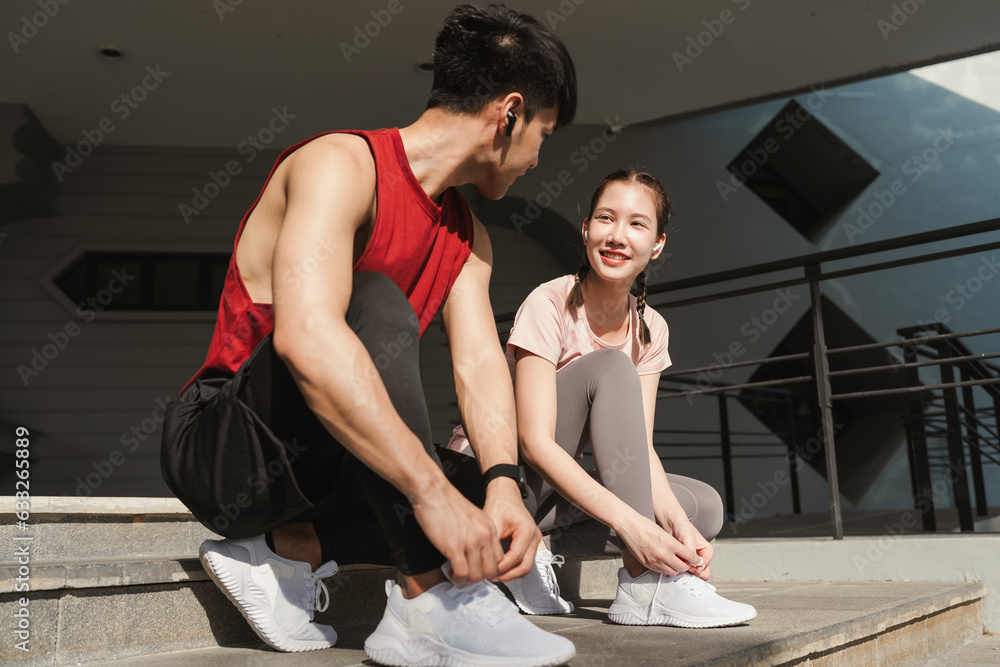 Obraz premium Preparation before jogging exercise. Together young Asian man and woman tying shoelace on her running shoes. Fitness and sport activity. Healthy exercise concept.