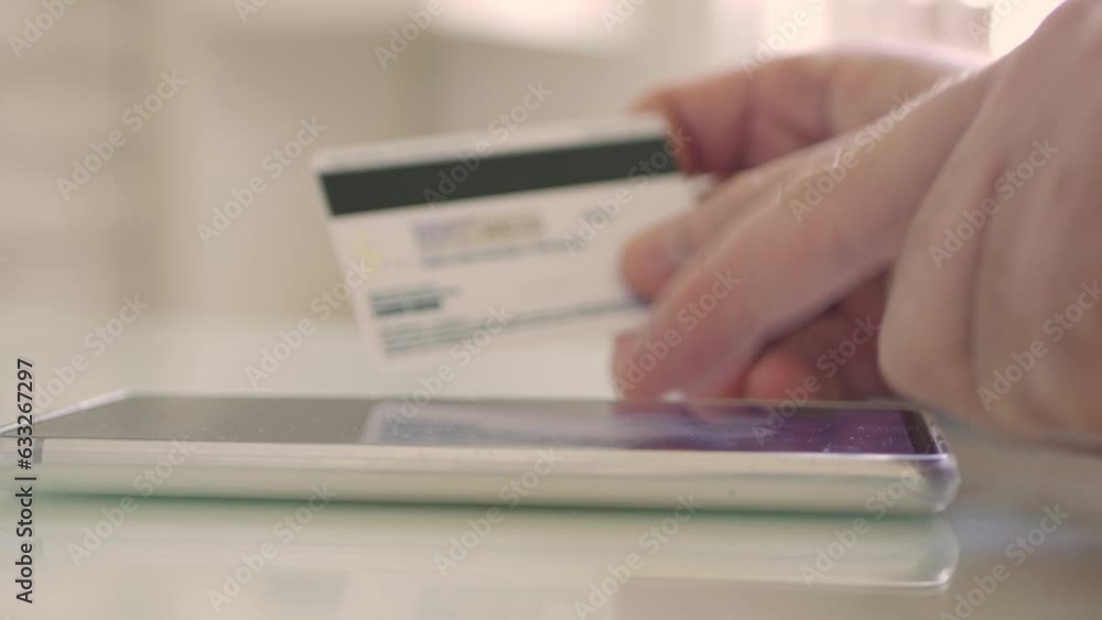 Blurred Shooting with a Person Making an Online Payment Using a mobile and a credit card, introducing online payment information. Shopping and Paying Online with a Credit Card. Blurred Shooting with a Person Making an Online Payment Using a mobile and a credit card, introducing online payment information. Shopping and Paying Online with a Credit Card.