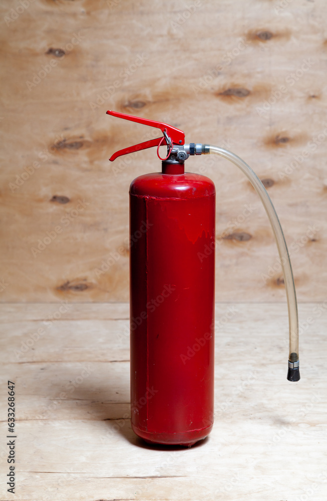 Red fire extinguisher on wooden background.. Red fire extinguisher on wooden background..