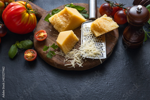 Cooking background with ingredients for preparation healthy food parmesan cheese, basil leaves, cherry tomato and olive oil on dark table top view, copy space